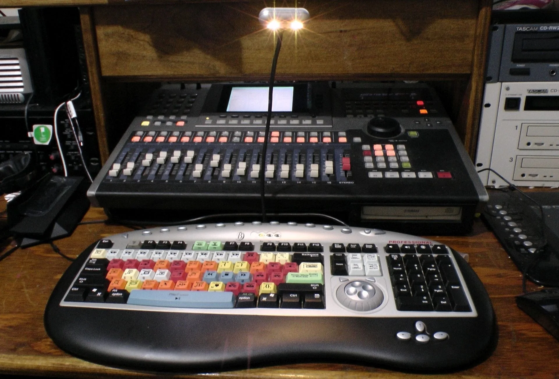 Mesa de edição de vídeo profissional com teclado colorido de atalhos e console de controle para produção audiovisual.